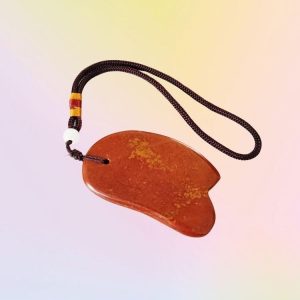 Natural Red Bian Stone Gua Sha Tool glowing with energy for holistic wellness