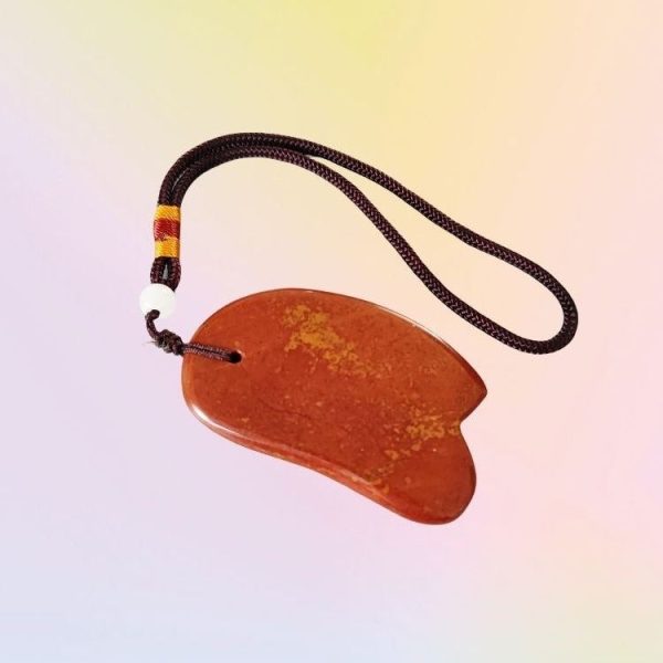 Natural Red Bian Stone Gua Sha Tool glowing with energy for holistic wellness